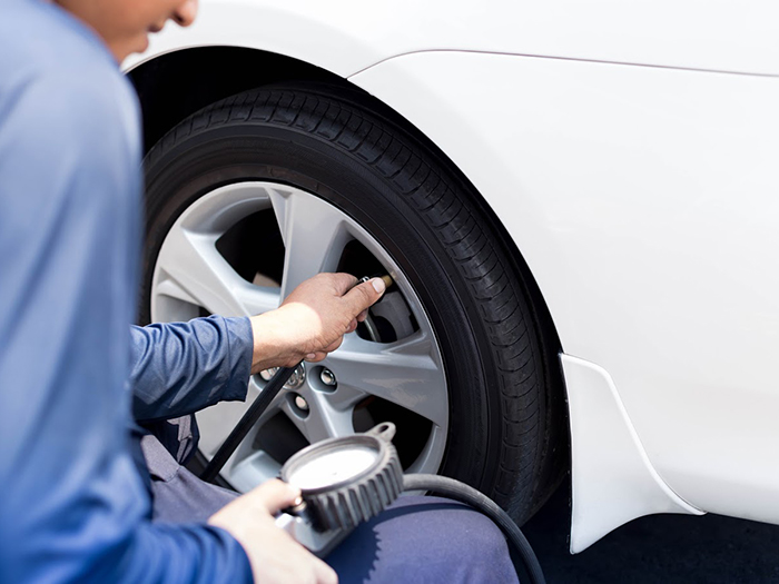 Man checking tire air pressure with gauge